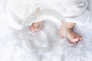 Cute newborn baby foot girl in white blanket onÂ nurseryÃ‚Â bed.Ã‚Â AdorableÃ‚Â new born child people Family.